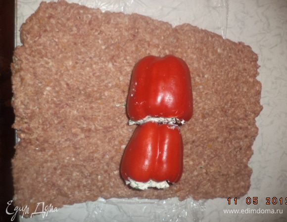 На стол постелить пищевую плёнку. На плёнку выложить пластом мясную массу. Сверху на мясной пласт выложить фаршированные перцы впритык друг к другу.