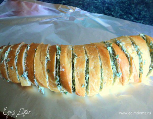 Багет надрезать, не доходя до края, на кусочки толщиной 1.0-1.5 см. Щедро промазать кусочки маслом с зеленью.