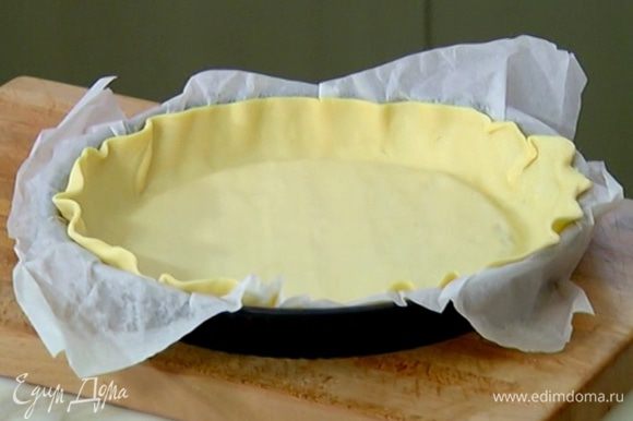 Форму для выпечки выстелить бумагой, выложить тесто, равномерно распределить по дну и бокам и часто наколоть вилкой.