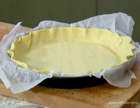 Форму для выпечки выстелить бумагой, выложить тесто, равномерно распределить по дну и бокам и часто наколоть вилкой.