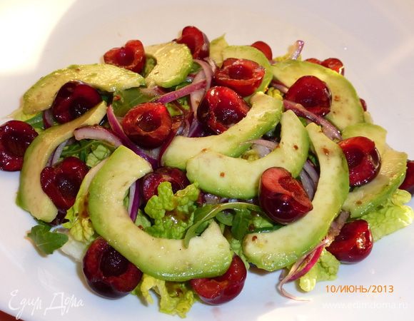 Собираем салат. На тарелку выкладываем листья салата, поливаем их заправкой. Далее лук, авокадо и черешня, поливаем заправкой. 