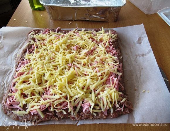 Сверху выкладываем нарезанную колбасу или ветчину. Затем тертый сыр...