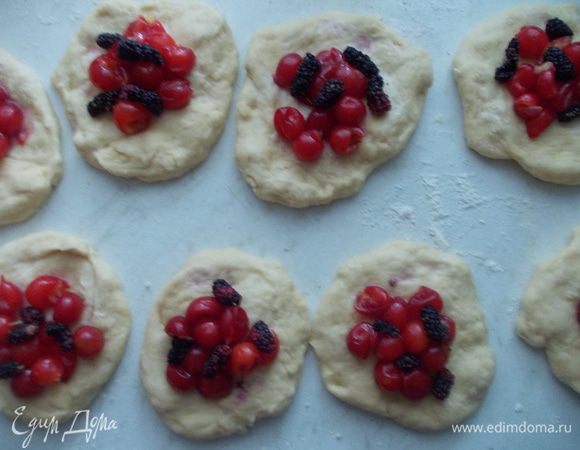 Делим тесто на небольшие кусочки, немного их разминаем в лепешку. На каждый кусочек теста раскладываем вишню с шелковицей.