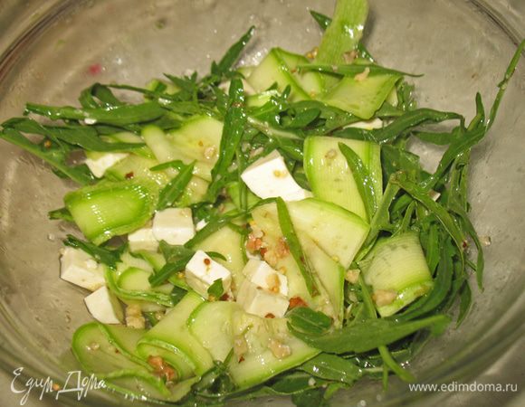 В другой салатник кладем вымытые и высушенные листья руколы, порезанную квадратиками брынзу, кабачки вместе с маринадом. Все аккуратно перемешиваем добавляем 1 ст.л. лимонного сока (по необходимости), оливковое масло, солим и перчим по вкусу.  Добавляем орехи и еще раз перемешиваем. 