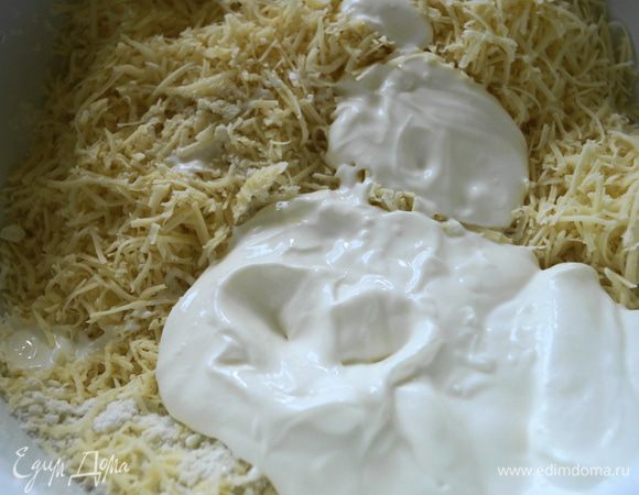 Добавить сливочное масло и растереть в крошку. Натереть сыр и прибавить к мучной массе, выложить сметану. Хорошо перемешать.
