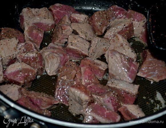 Говядину выложим на горячую сковороду с оливковым  маслом. Посолим и поперчим по вкусу и обжарим до полуготовности. Отставим в сторону или переложим в блюдо.