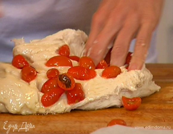 Ножницами сделать в тесте глубокие разрезы и в каждый разрез вставить вяленый помидор и листик базилика.