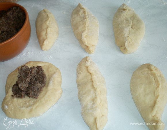 Когда тесто подойдет, нужно его положить на посыпанный мукой стол и раскатать в жгут, нарезать на  кусочки, слегка обвалять в муке, раскатать в лепёшку, положить начинку, защипнуть.