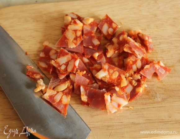 Колбасу нарезать мелкими кубиками. Добавить в подошедшее тесто и хорошо ее вмешать.