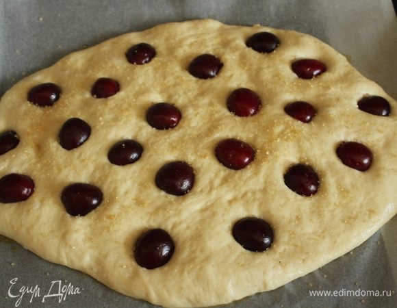 Подошедшее тесто посыпать коричневым сахаром и выложить черешню, слегка ее вдавив в тесто.