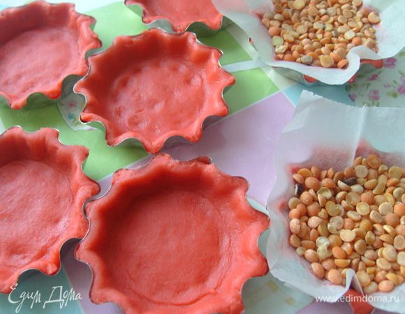 Охлажденное тесто раскатать в пласт толщиной 0,3 см., заполнить им формы для тарталеток. Положить бумагу для выпечки и сверху заполнить горохом или фасолью. Выпекать в разогретой до 180 градусов духовке 15-20 мин.