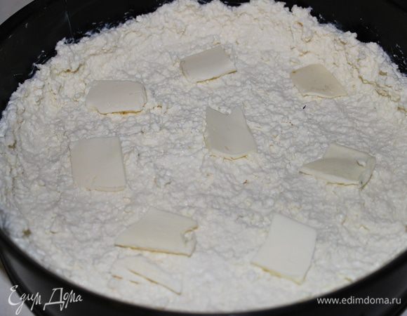 Выложить аккуратно 2/3 части творожной массы, сверху разложить тонкие кусочки масла (1/2 часть). Творожную массу лучше немного приподнять по краю формы, чтобы впоследствии фруктовый сок не вытекал наружу
