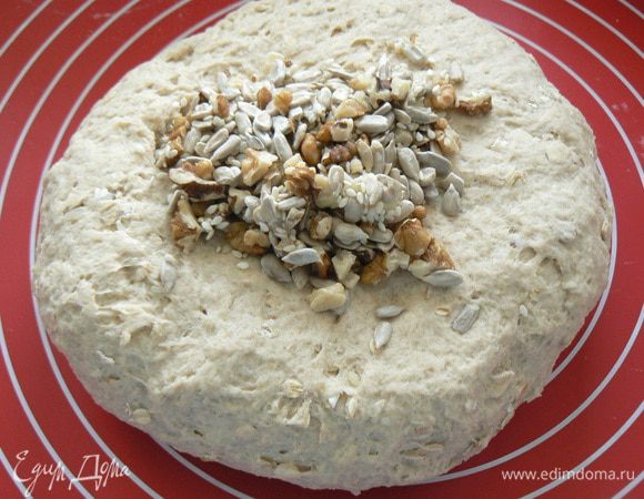 Орехи и семечки прокалите по отдельности в духовке или на сковороде без масла. Порубите орехи.
Выложите тесто на подпыленную мукой рабочую поверхность, расплющите в пласт, посыпьте орехами и семечками, сложите конвертом и вымесите еще раз, чтобы орехи равномерно распределились в тесте. 