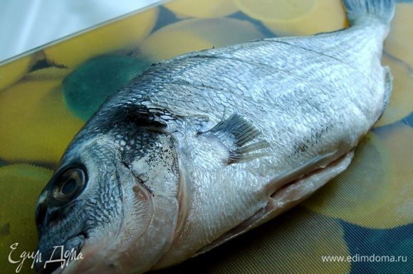 На очищенной и промытой рыбе сделать по три надреза с каждой стороны. Посолить рыбу внутри и снаружи и выложить на противень, застеленный фольгой.
