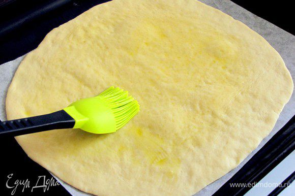 Тесто разделить на 2 равные части. Каждую часть разделить еще на две части. Раскатать тесто в круг и перенести на противень, застеленный пекарской бумагой. Поверхность лепешки смазать оливковым маслом.