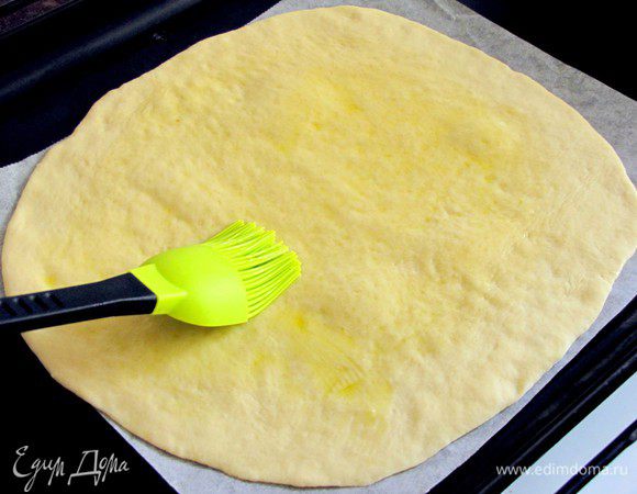 Тесто разделить на 2  равные части. Каждую часть разделить еще на две части. Раскатать тесто в круг и перенести на противень, застеленный пекарской бумагой. Поверхность лепешки  смазать оливковым маслом.