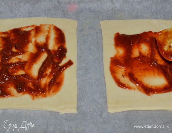 Раскатываем тесто, затем разрезаем на квадраты, должно выйти 6 квадратов. Каждый квадрат смазываем кетчупом или томатным соусом по центру,не задевая кончики краев.