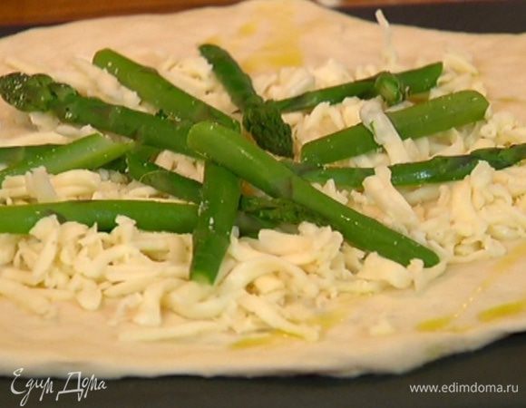 Поместить тесто на перевернутый противень, сбрызнуть оливковым маслом, посыпать моцареллой и таледжо, выложить спаржу, посыпать половиной пармезана и отправить в разогретую духовку на 6–8 минут.