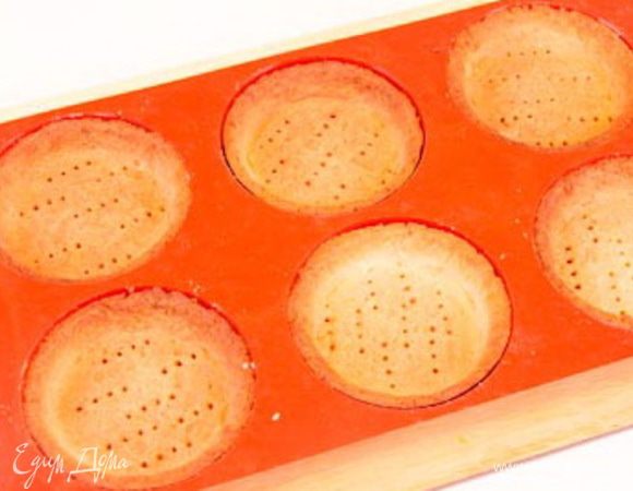 Раскатать тесто в пласт толщиной до 0,3 см. Убрать в холодильник на 5 минут.
Вырезать круги диаметром 11 см. Убрать в холодильник на 5 минут. Уложить круги из теста в формочки диаметром 8 см и дать ему осесть. Сформировать бортики, обрезать лишнее тесто. Убрать в холодильник.
Разогреть духовку до 170 С. Выпекать тарталетки с грузом 15 минут и  еще без груза 5-7 минут до золотистого цвета. Вынуть из духовки. Остудить. 
*Обрезки теста можно хранить несколько дней в холодильнике или 1 месяц в морозильнике. Из них можно сделать простое печенье.
