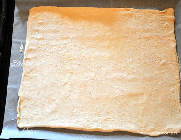 Тесто разморозить, раскатать в прямоугольный пласт и выпекать в заранее нагретой до 200 С духовке 25 минут