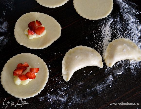 Вырезать кружочки (примерно 6 см в диаметре) и в центр каждого кружочка положить по 1 чайной ложке заварного крема и клубники. Закрыть кружочки теста и как следует плотно закрепить края и сформировать "полумесяцы". )))  