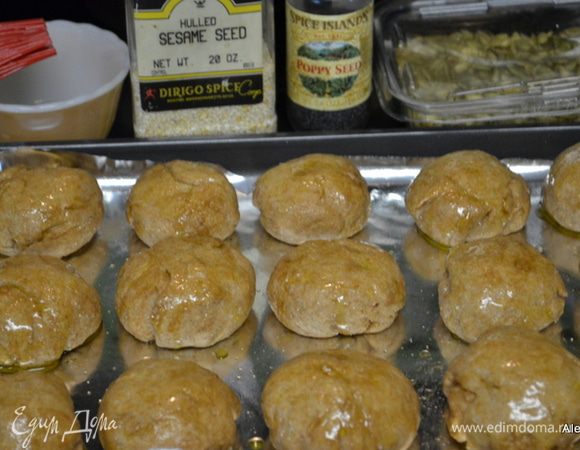 Как шарики поднялись, кисточкой нанести желток на каждый шарик. Или можно опять промазать растит. или олив. маслом. Выложить поверх каждой булочки семена кунжута, мака и семечек. Поставим в духовку разогретую на 200 гр. на 8-10 мин.
