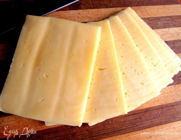 Сыр нарезаем плотными ломтиками вдоль куска...