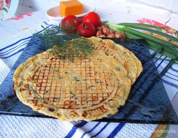 На мелкой терке натереть сыр. Мелко нашинковать зелень и зеленый лук. Включить вафельницу разогреваться. Яйца взбить с сахаром, добавить воду с молоком, разрыхлитель и просеянную муку. Затем вмешать зелень и сыр. Хорошо перемешать. Тесто должно быть как очень густая сметана. Это регулируется при помощи увеличения количества муки на 2-3 столовых ложки.
В конце добавить в тесто растительное масло и выпекать до золотистого цвета. 
Если кто-то любит хрустящие вафли, два совета.
1. Вафли не складывать вместе. а остужать по отдельности.
2. Можно включить духовой шкаф на режим круговой вентиляции с минимальной температурой, и подсушивать вафли там.