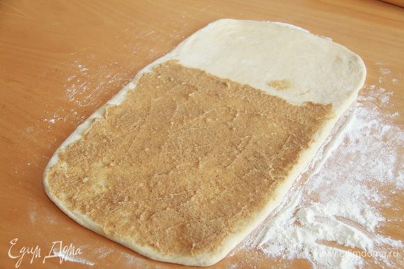 Тесто и начинка готовы, можно делать булочки. Рабочую поверхность присыпать щедро мукой. Раскатать тесто в прямоугольник толщиной 3-4 мм. На 2/3 прямоугольника намазать начинку.