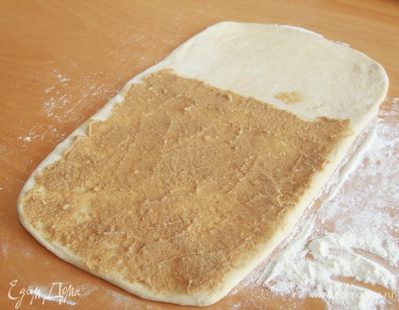 Тесто и начинка готовы, можно делать булочки. Рабочую поверхность присыпать щедро мукой. Раскатать тесто в прямоугольник толщиной 3-4 мм. На 2/3 прямоугольника намазать начинку.