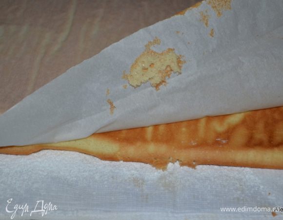 Пока готовится бисквит приготовим полотенце тонкое. Просеять сахарную пудру на поверхность полотенца в размер противня. Осторожно снять с противня бисквит с бумагой поддерживая свободные концы и перевернуть на полотенце с сахарной пудрой. Снимем бумагу.