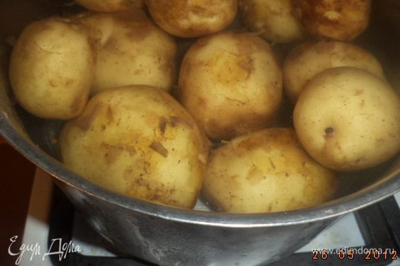 Картофель тщательно вымыть. Не очищая, варить в подсоленной воде около 15-20 минут, до мягкости. Воду слить, картофель слегка остудить.