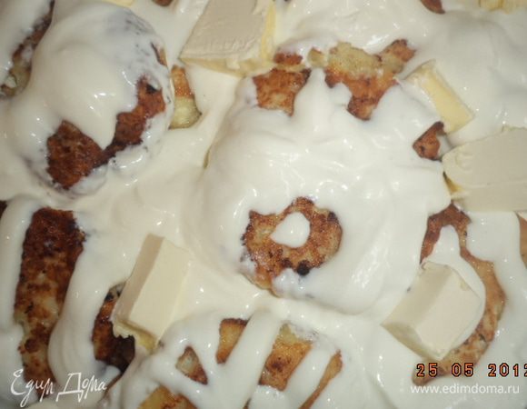 Сложить сырники в форму для запекания, полить сметаной. Сверху разложить кубики сливочного масла. Запекать при температуре 200 градусов 15 - 20 минут.