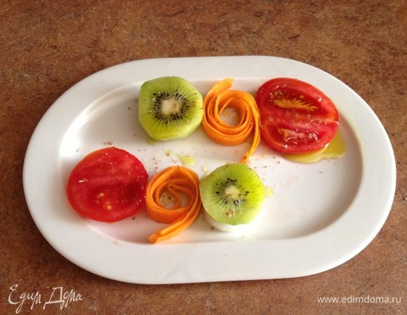 Уложить на тарелку в виде «светофорчика»: помидор, скрученная ленточка из морковки,  лук, а на него киви (киви своей кислинкой немножко промаринует лучок).
В ступке растолочь семена кориандра с солью, добавить оливковое масло. Полученной смесью полить овощи.