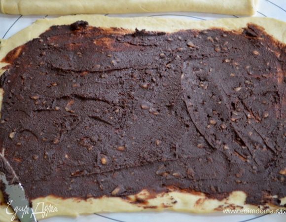 Тесто для рулетов поделить на 2 части или если крупный противень можно оставить одним куском. Раскатать.
Пасту распределим по тесту,оставляя края. Если у вас две части теста, то пасту предварительно поделить.
Проделаем со второй частью также.