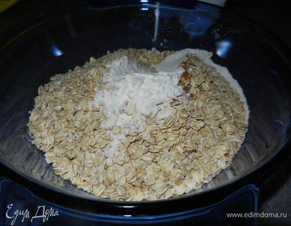 Просеять муку вместе с содой, солью и корицей. Всыпать овсяные хлопья.