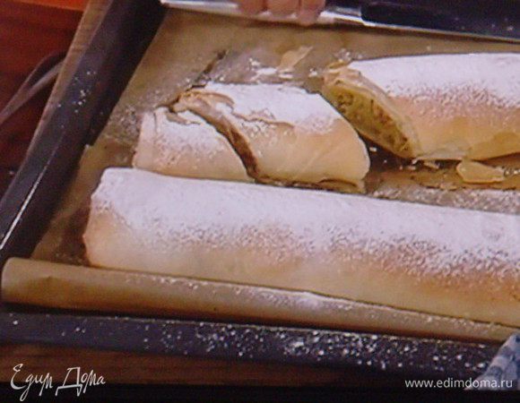 Вынуть штрудель из духовки, присыпать пудрой. Дать ему маленько остыть. Разрезать на порции. Для этого необходим острый нож, т.к.  тесто очень ломкое. Красиво смотрится, когда штрудель режут немного наискосок. 