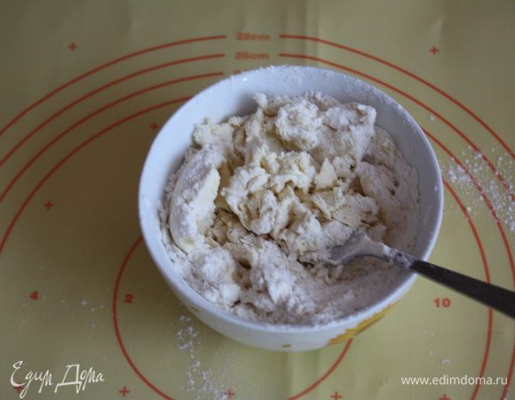 Разминаем его вилкой, добавляем просеянную муку и замешиваем масляное тесто.