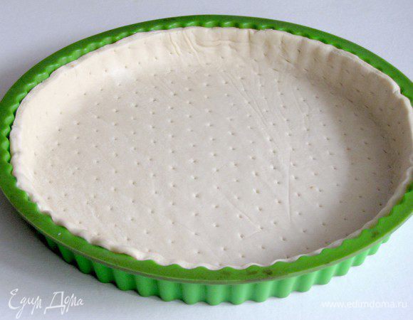 Выложить в круглую форму слоеное тесто, обрезать лишнее, сделать вилкой несколько проколов.