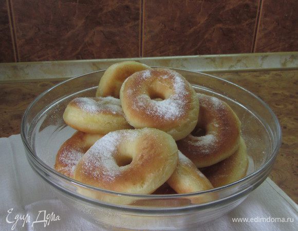 Присыпаем сахарной пудрой и сразу подаем на стол. Пончики всегда особенно хороши при подаче на стол горячими – как говорится, с пылу, с жару. 
