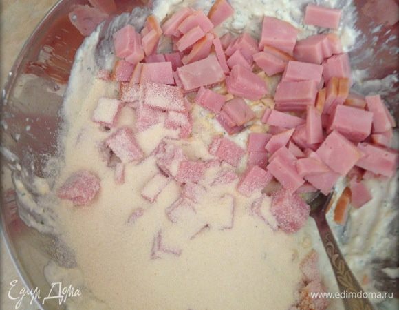 Нарезать небольшими кубиками ветчину, мелко нарезать чеснок, добавить в тесто. Насыпать манку, тщательно перемешать. Отставить минут на 15-20