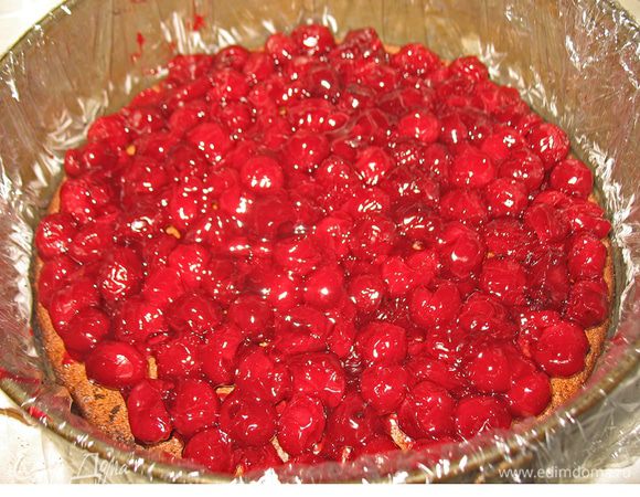 Форму застелить пленкой. В нее положить корж, сверху на корж выкладываем вишню. Я еще теплую вишню доставала из киселя и выкладывала на корж. Отставила в сторону до полного остывания вишни. 