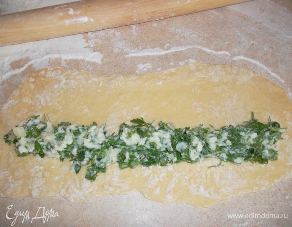 Тесто режем на кусочки и раскатываем в длинненькие лепешки. На край лепешки выкладываем дорожкой начинку...