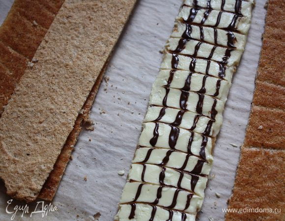 Пока глазурь не застыла, наносим 4 вертикальные полосы из черного шоколада и зубочисткой проводим полоски в разные стороны. Сначала в одну, потом в другую.