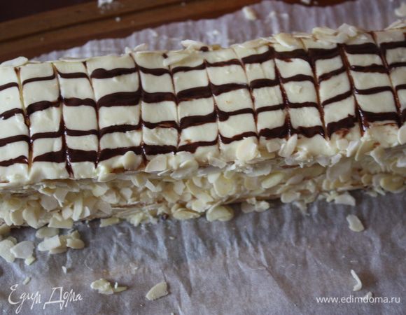 А сверху укладываем нашу полоску с глазурью. Бока смазываем немного кремом и посыпаем миндальными лепестками.