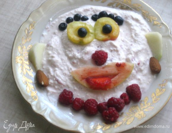 Абрикосу разламываем не до конца. Кладём вверху, это будут глаза. Внутрь по 1 черничке. Чуть ниже вставляем малинку. Вырезаем из дольки яблока ротик и подкрашиваем клубничным джемом. Кладём на крем и вставляем в отверстие во рту клубничный слайс. Дальше делаем брови из черники, уши из яблока. Миндальные серёжки и малиновое ожерелье.