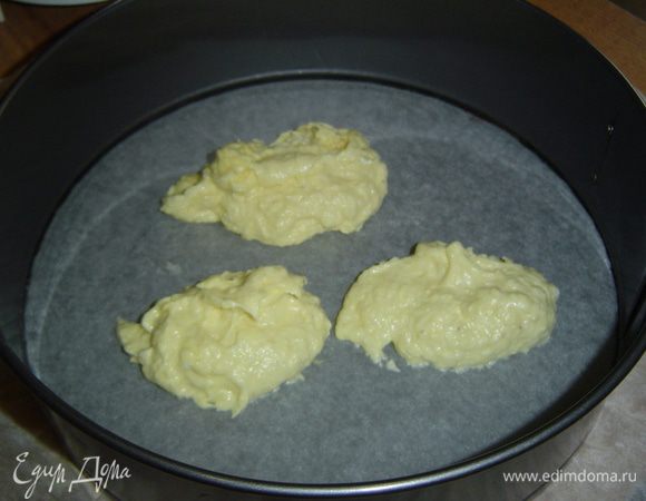 Разъемную форму (26 см) застилаем пергаментной бумагой и на дно кладем три столовые ложки теста, распределяем по всей поверхности тонким слоем и отправляем в духовку, разогретую до 200-220 градусов, на 3-4 минуты до золотистого цвета.