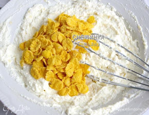 Кладём кукурузные хлопья. Перемешиваем. Оставляем. За время, пока остынет корж, хлопья успеют набухнуть, благодаря имеющейся жидкости.