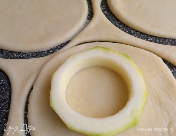Отлежавшееся тесто раскатываем и вырезаем из него кружки по размеру больше чем кольца кабачка