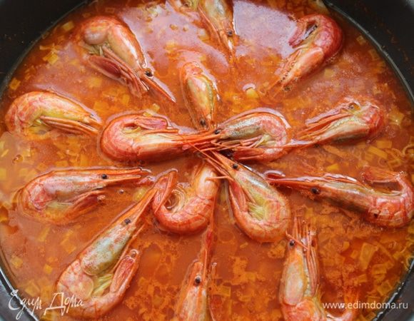 Рис высыпать в сковороду и равномерно его распределить, но не перемешивать!!! Бульон должен покрыть рис. Довести до кипения и разложить поверх риса креветки. Накрыть крышкой и готовить 10 минут на минимальном огне.